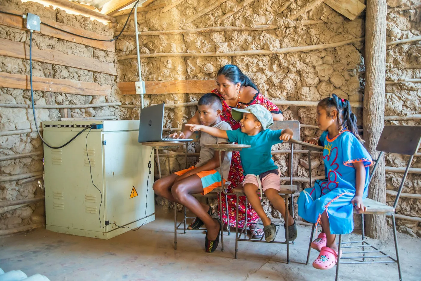 Teacher helping children learn with a laptop in a supported setting
