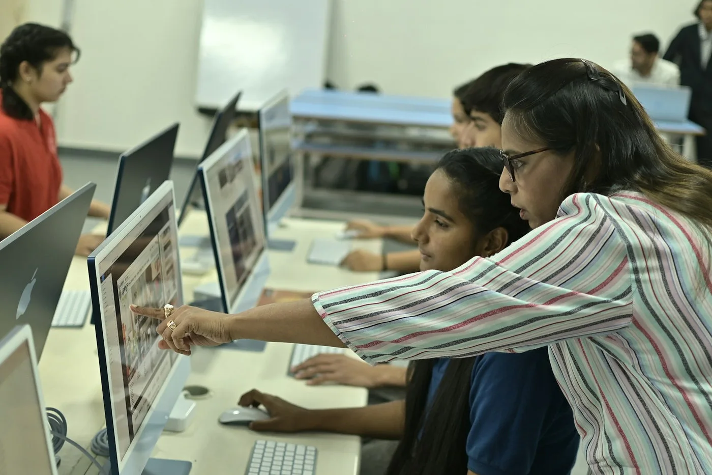 Teacher guiding students during a supervised computer learning session