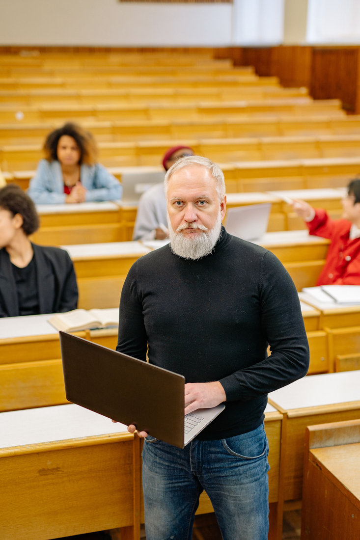 University professor using a laptop in a modern classroom