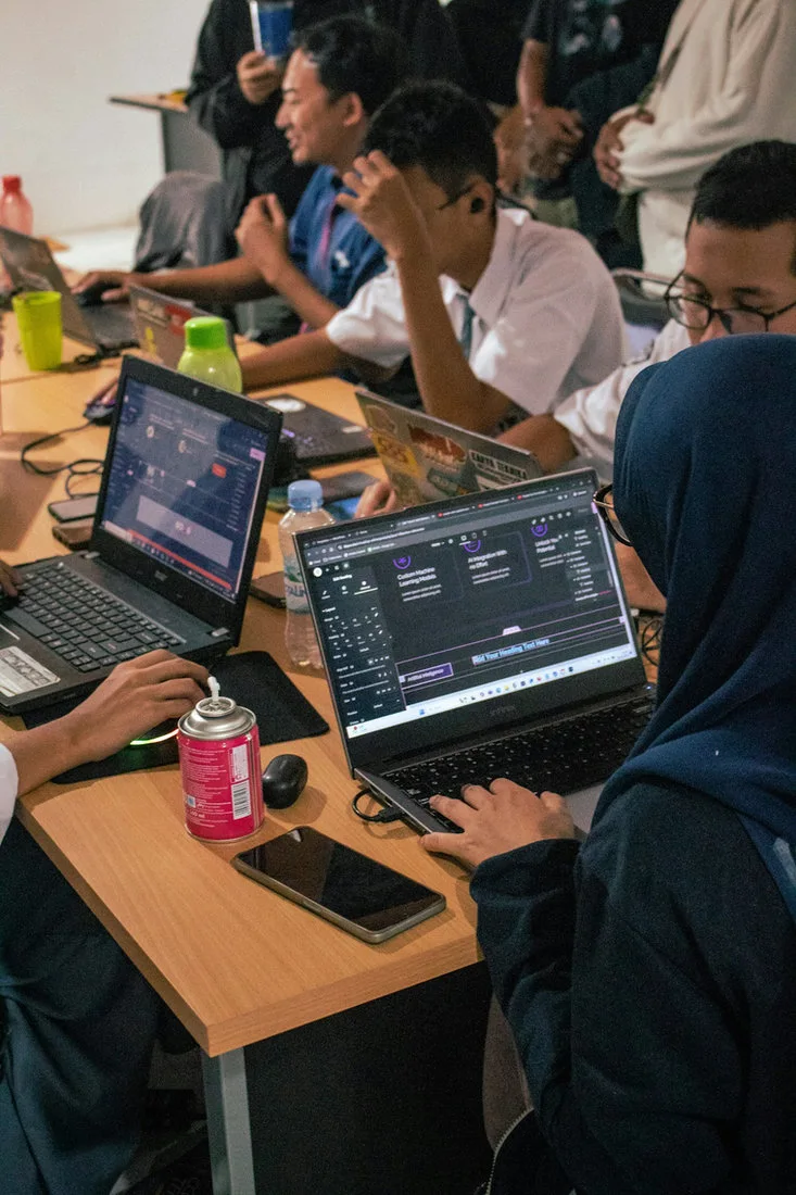 Students working together on laptops at a shared classroom desk