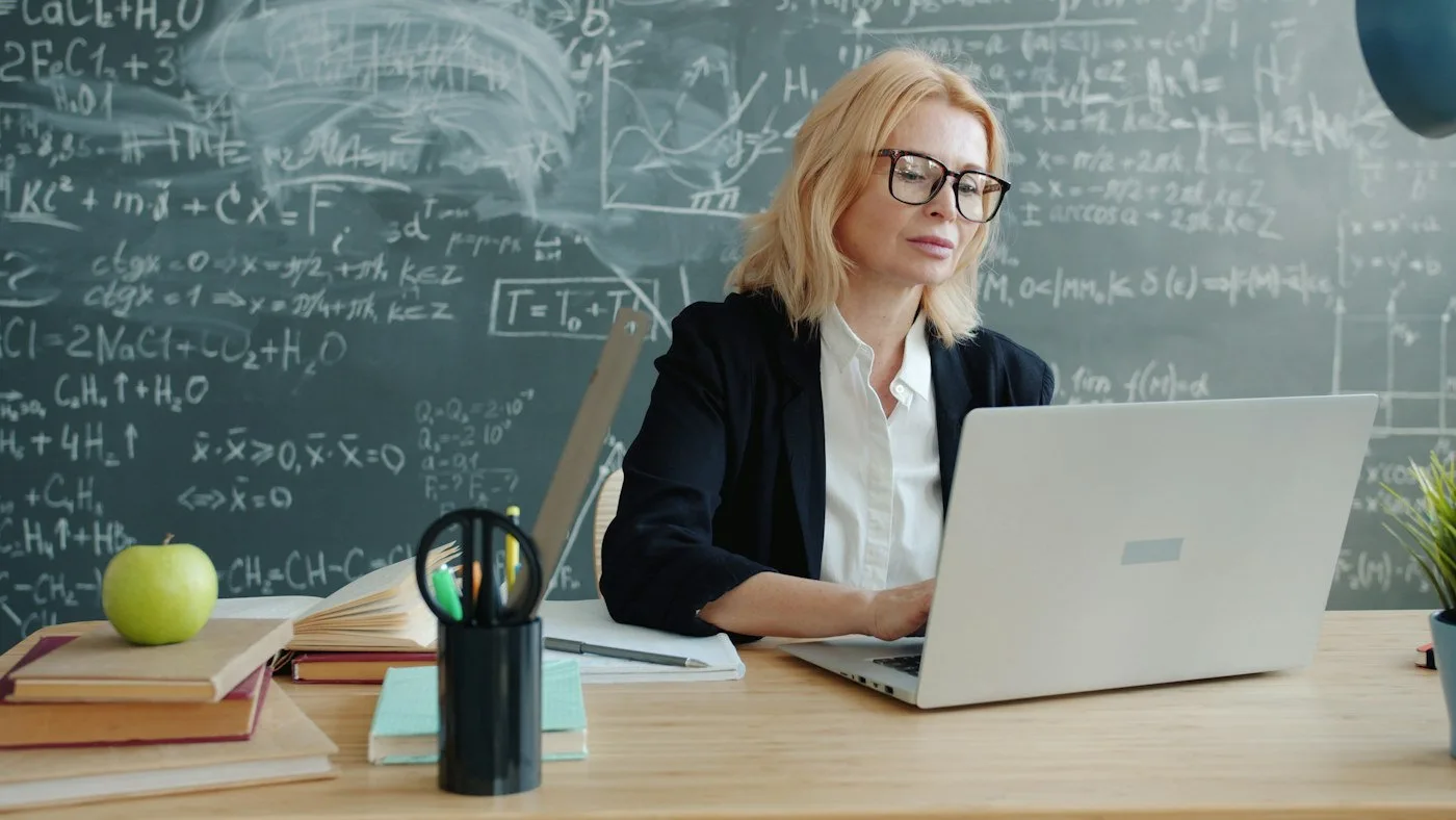 Teacher using a laptop to organise a classroom lesson
